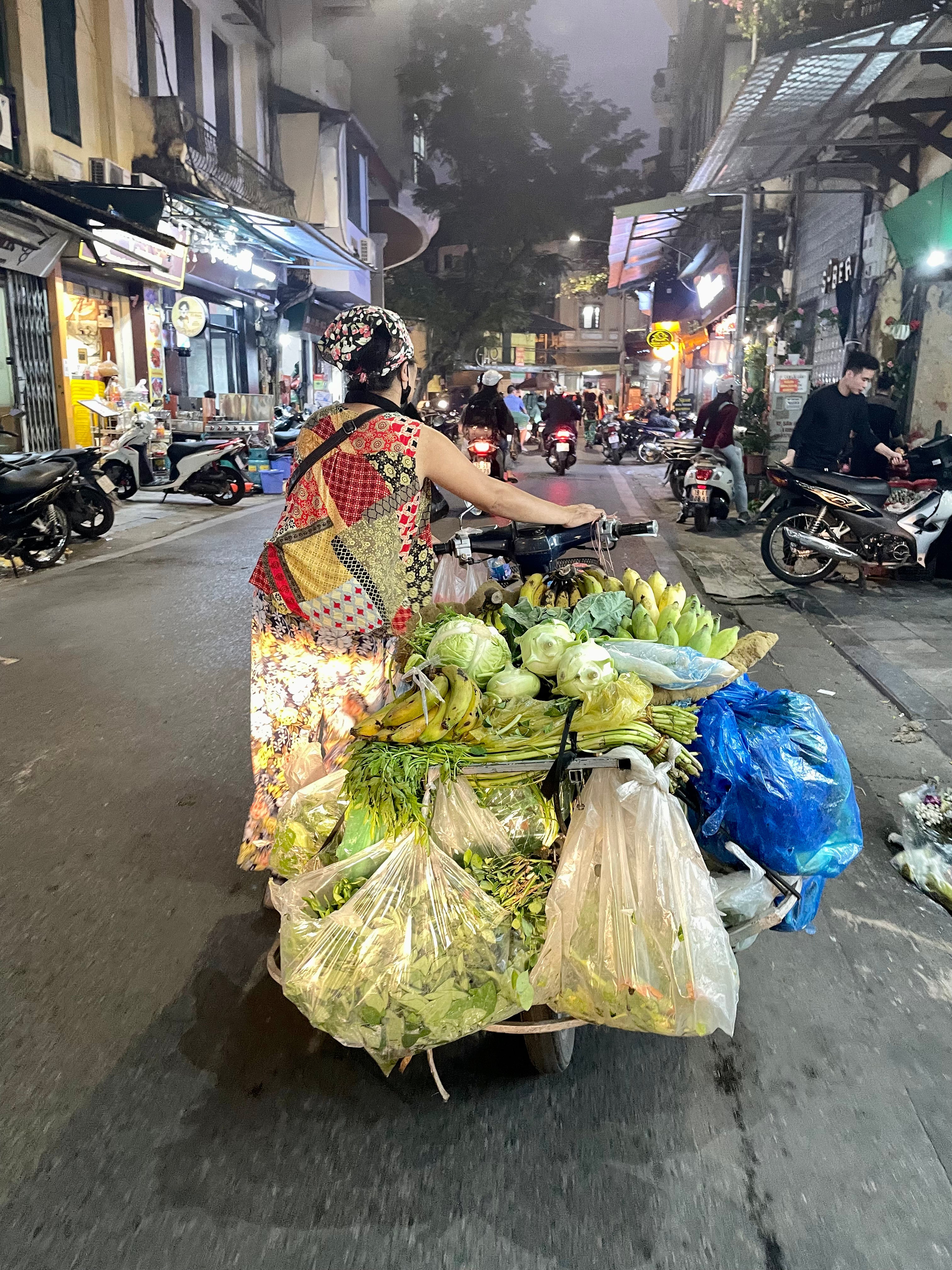Woman pushing motorbike oiled with food to sell
